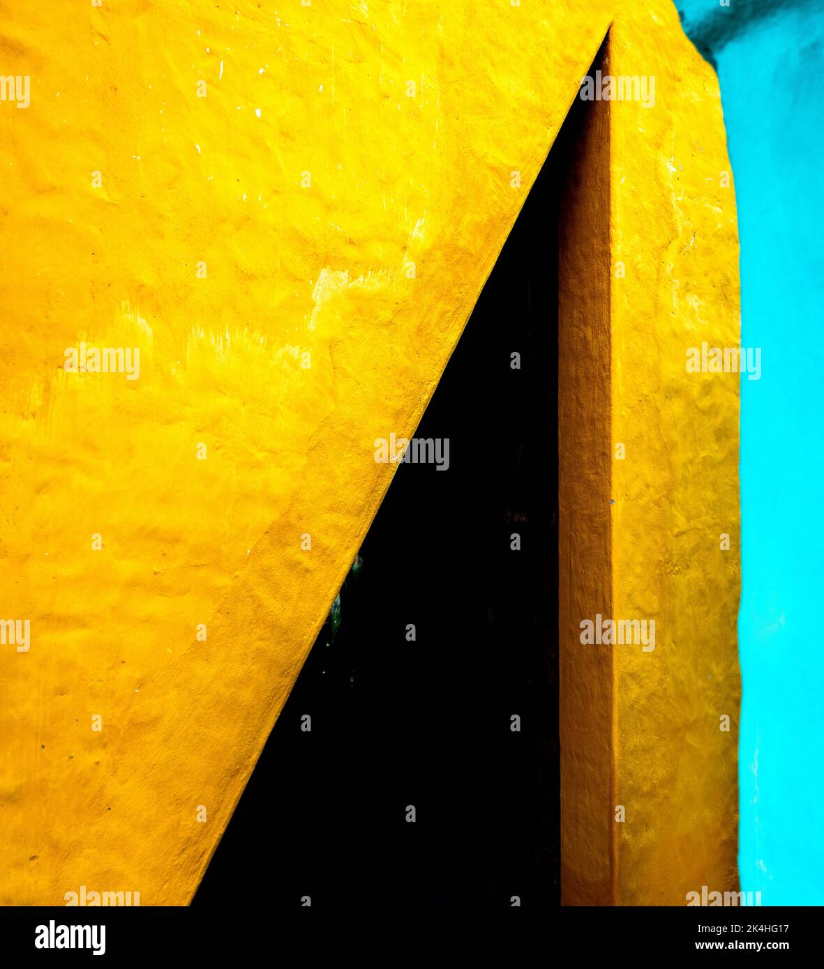 Scharfe Winkel in Türkis und Gelb auf einem Stuckgebäude. Stockfoto