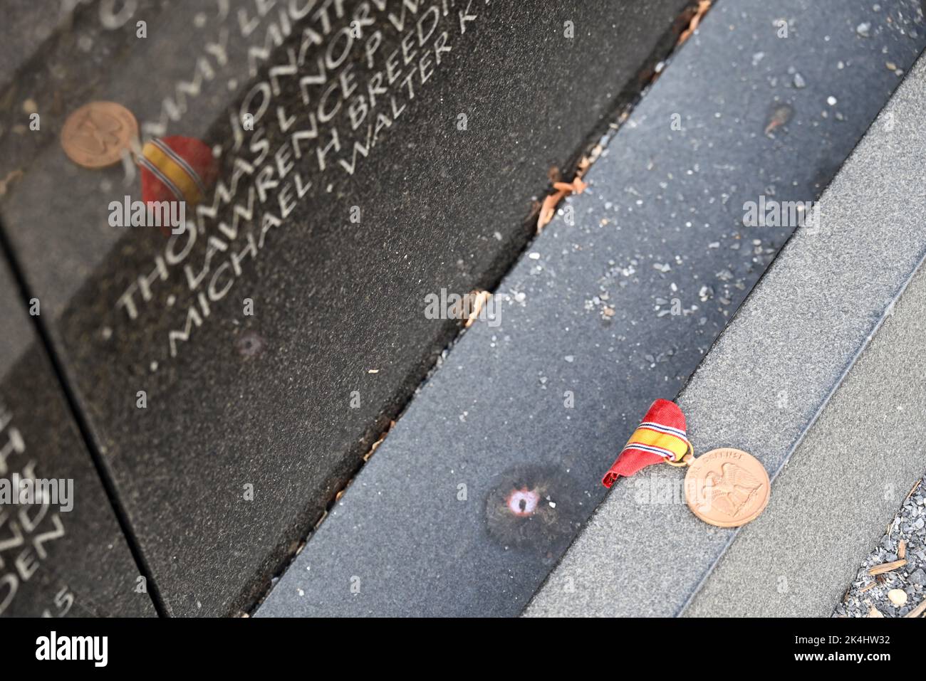 Eine Medaille des Nationalen Verteidigungsdienstes wird als Tribut an die Basis der Vietnam Memorial Wall in Washington, DC, hinterlassen. Stockfoto