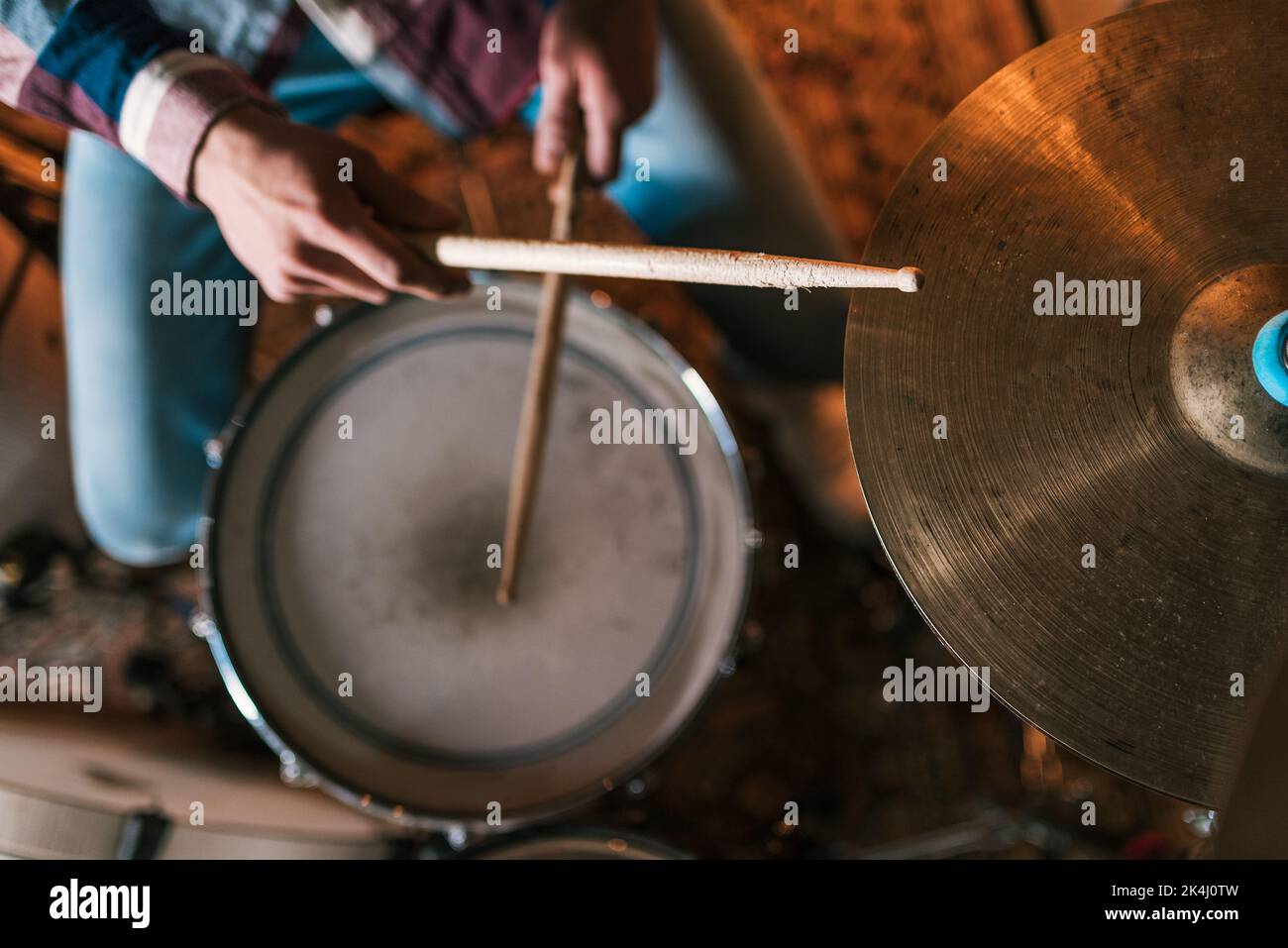High Angle of Crop anonymer männlicher Musiker mit hölzernen Drumsticks, die Rockmusik auf der Bühne spielen Stockfoto