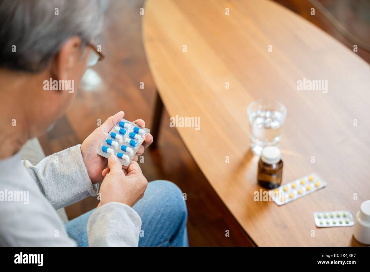 Asiatischer alter Mann kaufen pflanzliche Selbstkur Rx Pille online aus der Apotheke, besorgt Senior Mann mit Medikamenten Pillen, die er auf lesen, wie man Pillen vor der Einnahme zu nehmen Stockfoto