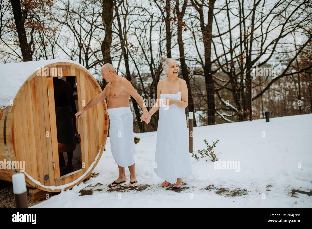 Ältere Frau in einem Handtuch mit ihrem Mann, der während des kalten Wintertages in die