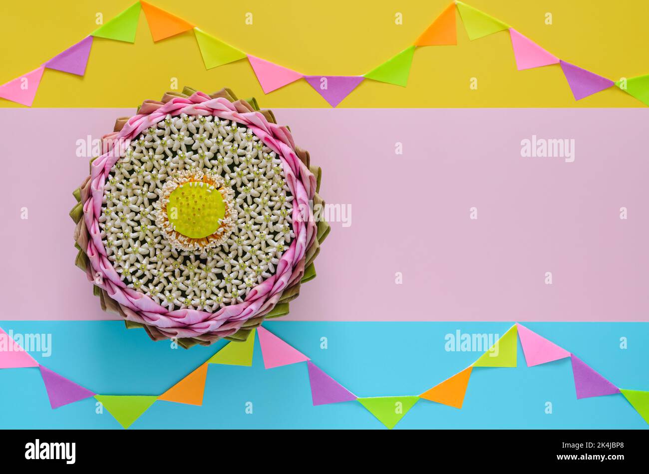 Das rosa Lotusblütenblatt krathong schmückt mit seinem Pollen und seiner Kronenblume für das Thailand Loy Krathong Festival auf buntem Hintergrund mit Party-Flagge. Stockfoto
