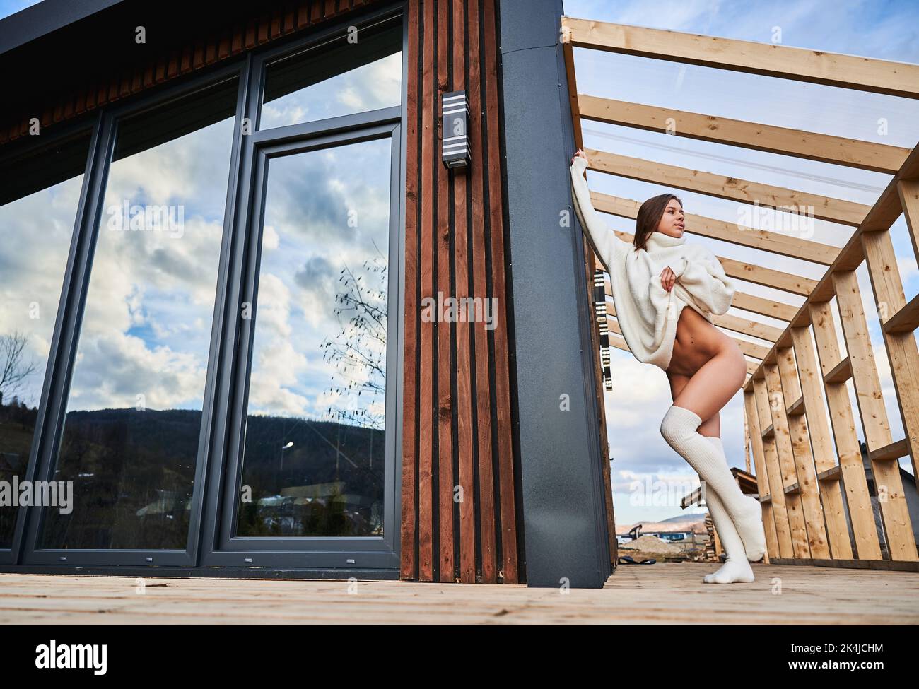 Junge nackte Frau im Freien auf der Terrasse des modernen Holzrahmenhaus. Stockfoto