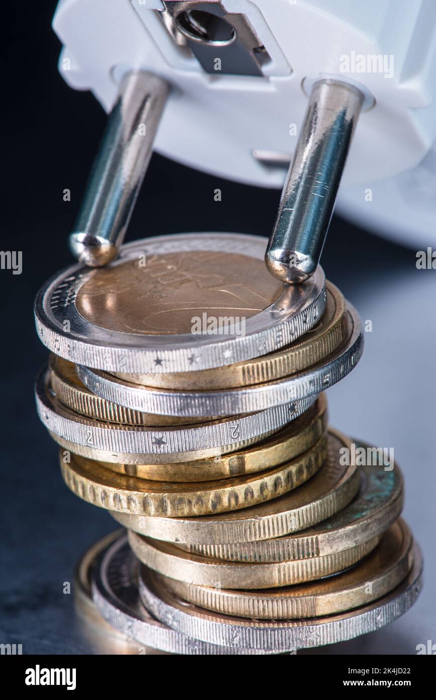 Haufen von Euro-Münzen und Steckdose, Konzept der steigenden Energiepreise Stockfoto