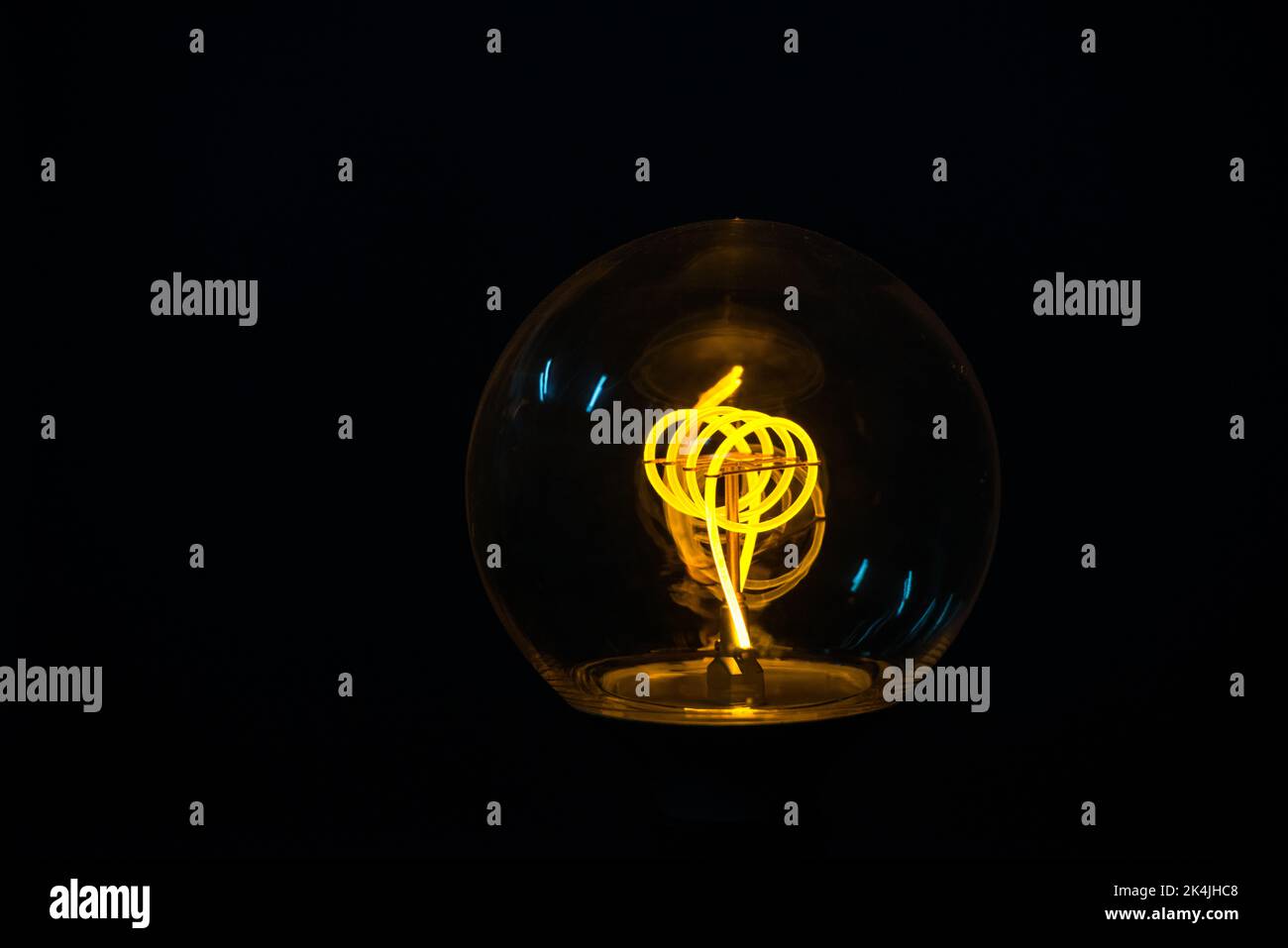 Eine klassische Edison-Glühbirne auf schwarzem Hintergrund mit Platz für Text. Beleuchtete Glühlampe auf schwarzem Hintergrund Stockfoto