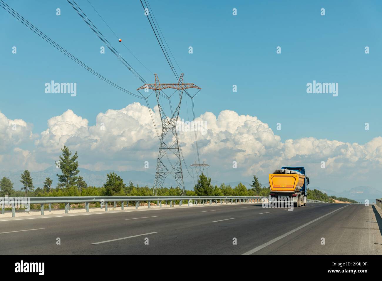 Ein LKW, der auf einer Autobahn fährt, und eine Hochspannungsleitung an der Seite der Autobahn Stockfoto