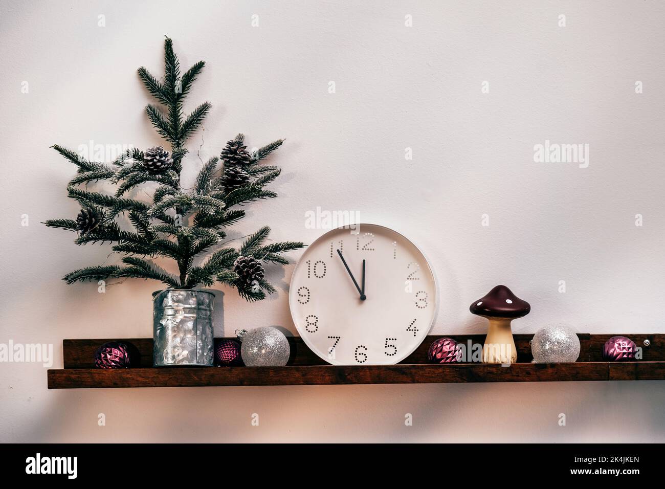 Weihnachtsbaum, weiße Uhr und Dekorationen vor der Holzwand Stockfoto