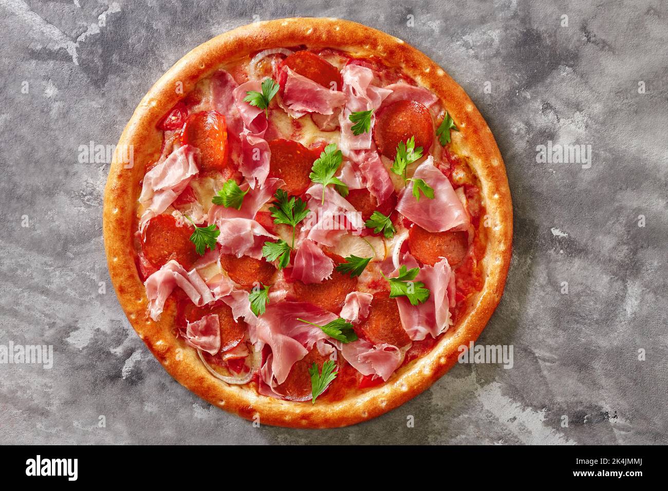 Fleischpizza mit Salami, geräuchertem Huhn, Schinken und Prosciutto auf grauer Steinoberfläche Stockfoto