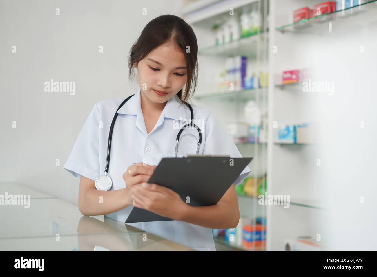 Medizin und Gesundheitskonzept, Apothekerin schreibt Rezept und medizinische Eigenschaften. Stockfoto