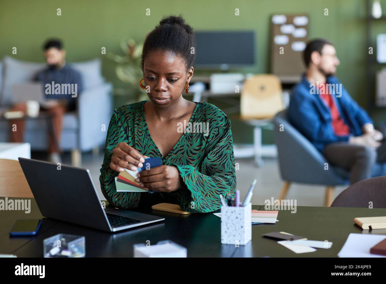 Junge ernsthafte afroamerikanische Designer mit Farbpalette Online-Videos auf Laptop-Bildschirm, um neue Informationen zu lernen Stockfoto