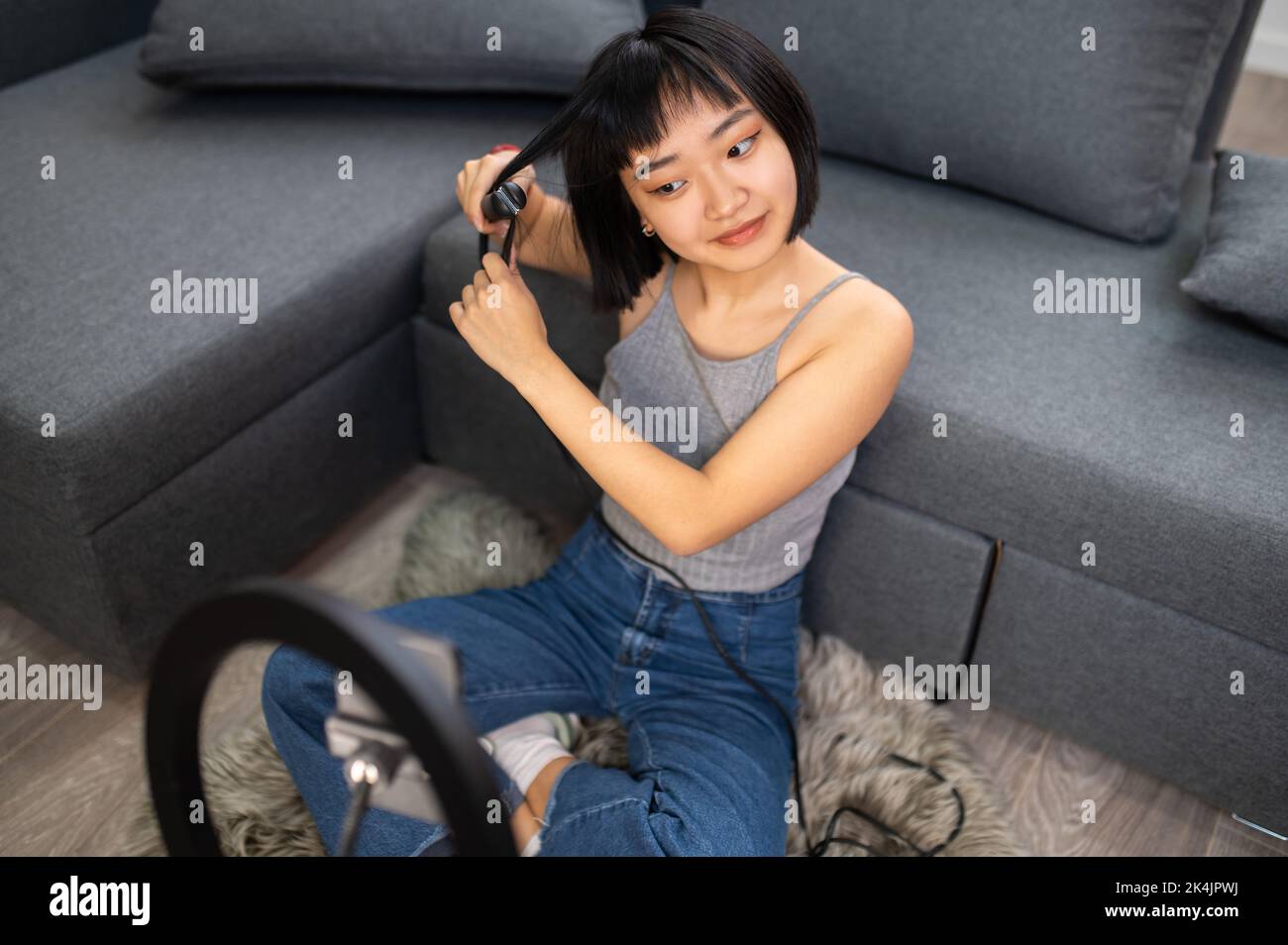 Videobloggerin mit einem Lockenstab in ihrem Beauty-Vlog Stockfoto