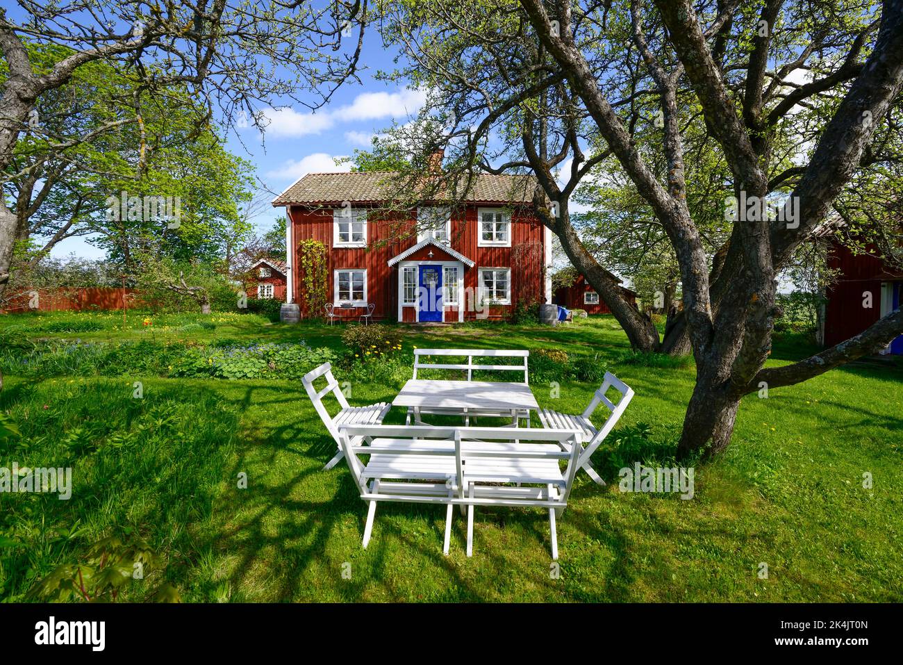Ein falurotes Wohnhaus mit Veranda und Garten mit Außenmöbeln vor der Tür, Sörmland, Schweden Stockfoto
