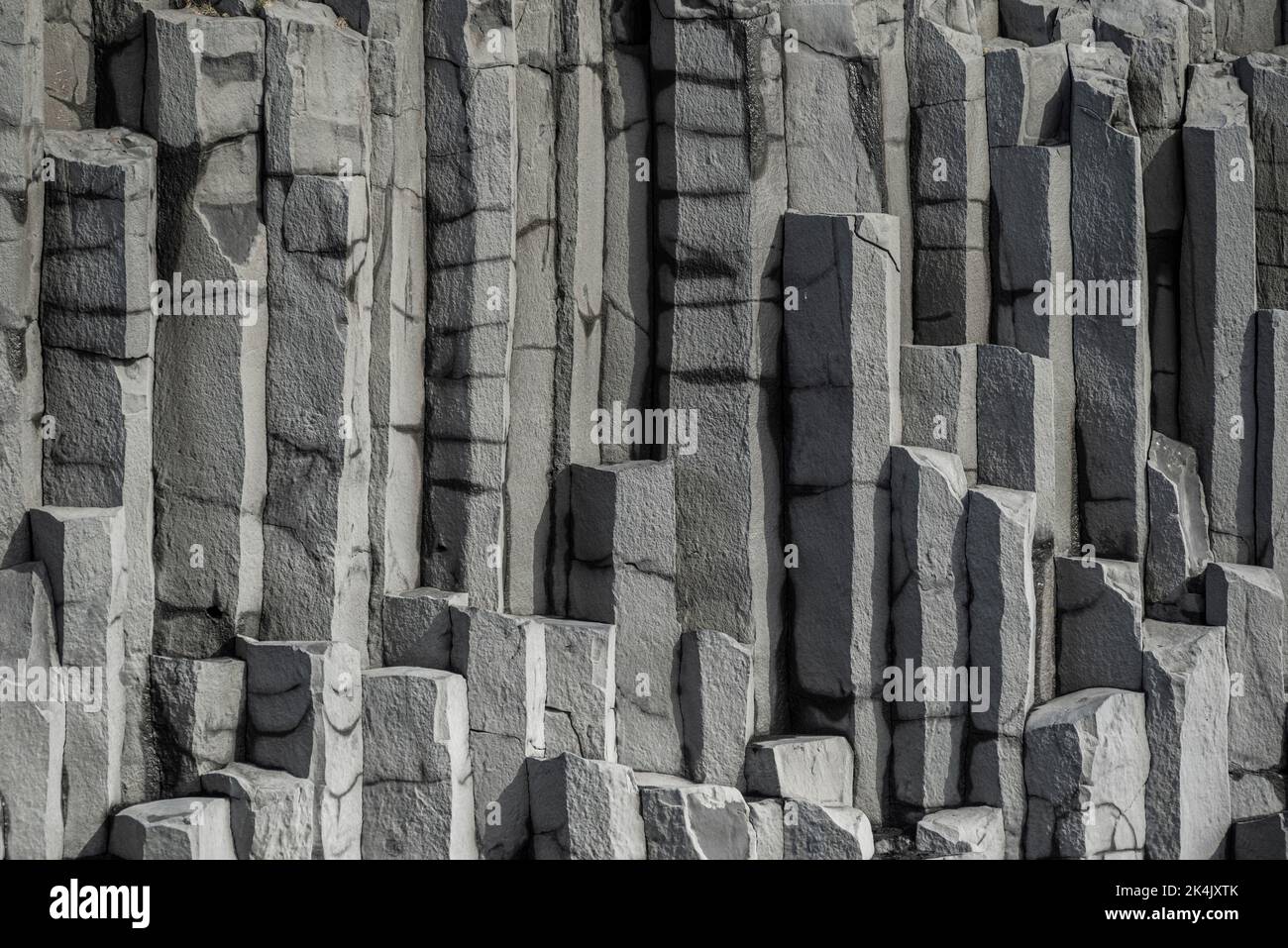 Vertikales Basaltsäulenhintergrundmuster, das die geometrischen sechseckigen Basaltfelsen des Reynisfjall-Berges, Reynisfjara-Strand, Island, zeigt Stockfoto