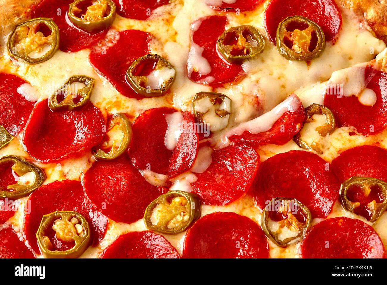 Stücke von Jalapeno auf der würzigen Pepperoni-Pizza mit geschmolzenem Mozzarella Stockfoto