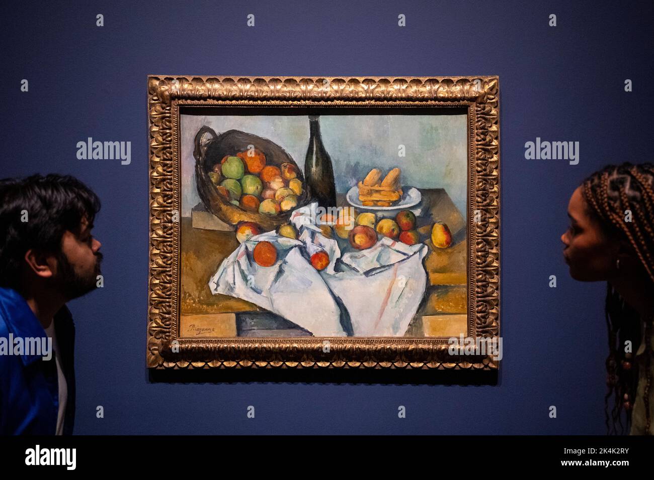 London, Großbritannien. 3. Oktober 2022. Die Angestellten sehen „The Basket of Apples“, c. 1893, von Paul Cezanne bei der Vorschau der EY-Ausstellung: Cezanne in der Tate Modern. Vom 5. Oktober bis 12. März 2023 werden 80 Gemälde, Aquarelle und Zeichnungen von Paul Cezanne mit Schlüsselbeispielen seiner ikonischen Stillleben-Gemälde, Provençale-Landschaften, Porträts und Baderszenen, darunter über 20 Werke, die in Großbritannien noch nie zu sehen waren, gezeigt. Kredit: Stephen Chung / Alamy Live Nachrichten Stockfoto