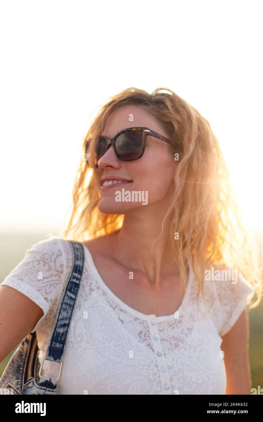 Junge kaukasische Touristenfrau, die sich im Sonnenuntergangsporträt umsieht Stockfoto