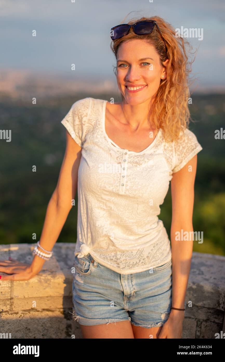 Glückliche junge kaukasische Touristenfrau posiert bei Steingeländer im Freien Stockfoto