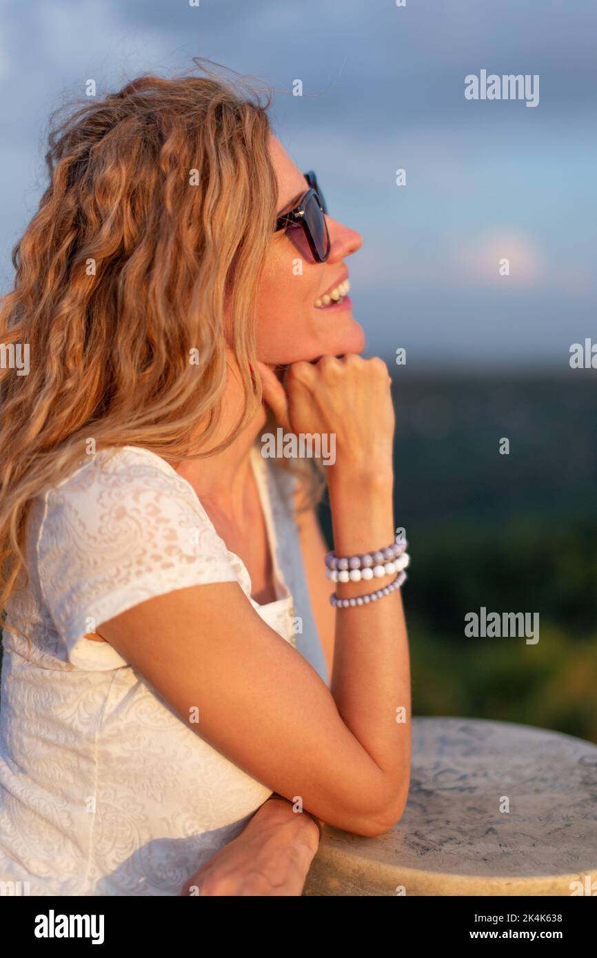 Junge, positive kaukasische Frau in Sonnenbrillen, die die Sonnenuntergangsmomente im Freien genießen Stockfoto