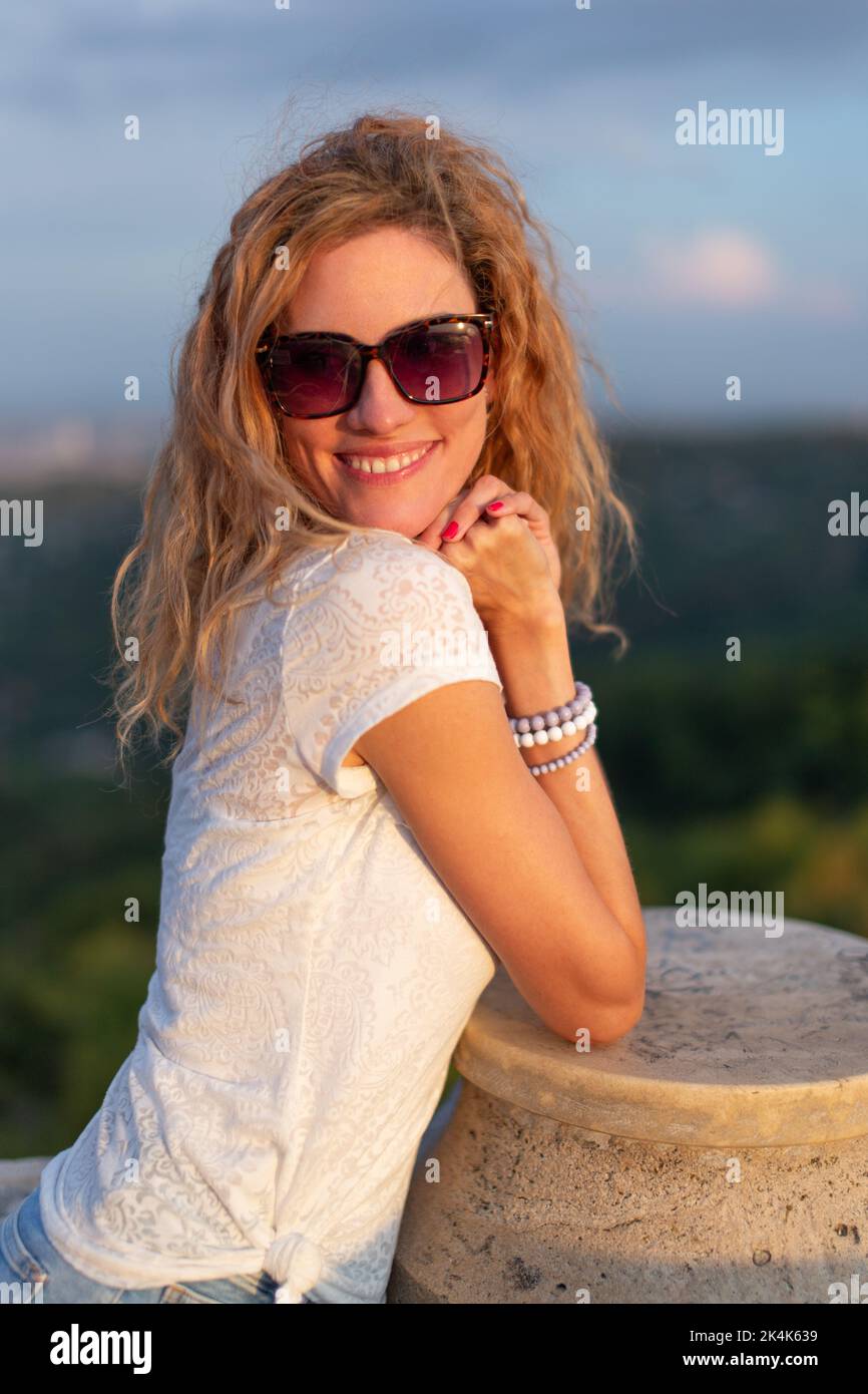 Junge positive kaukasische Frau in Sonnenbrillen posiert Sonnenuntergang im Freien Stockfoto