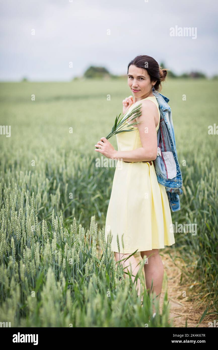 Lifestyle-Porträt einer jungen stilvollen Frau, die durch Weizenfeld geht Stockfoto