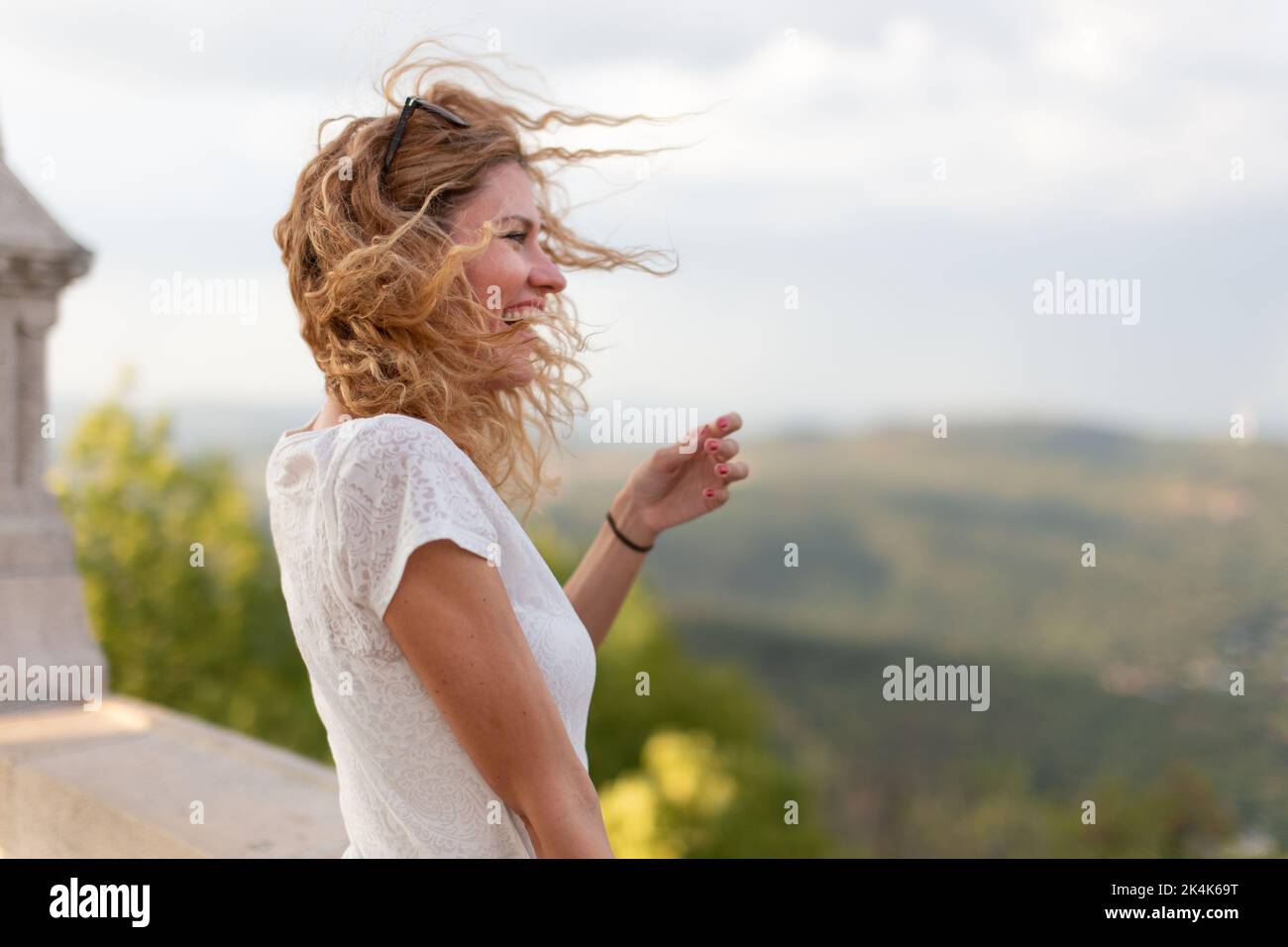 Kaukasische Frau mit lockigen Haaren lacht im Freien Profilansicht Stockfoto