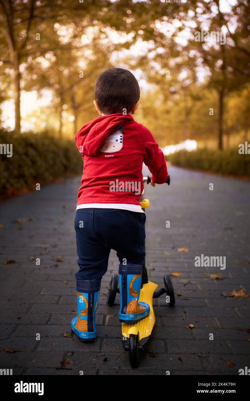 Kind spielt mit seinem Roller auf der Straße Stockfoto