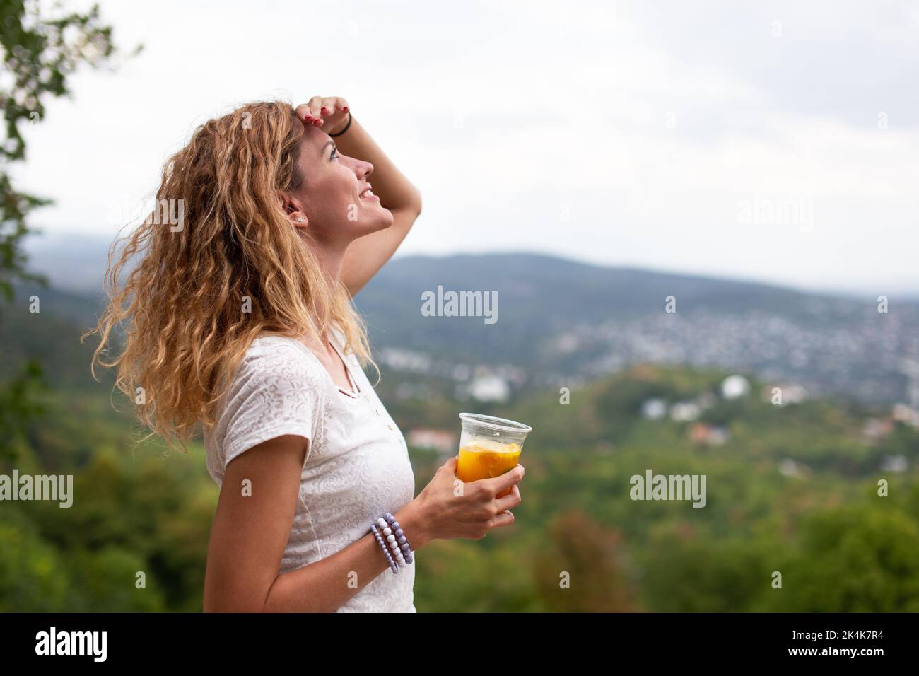 Junge kaukasische 30s Frau mit lockigen Haaren Blick auf den Himmel im Freien Stockfoto