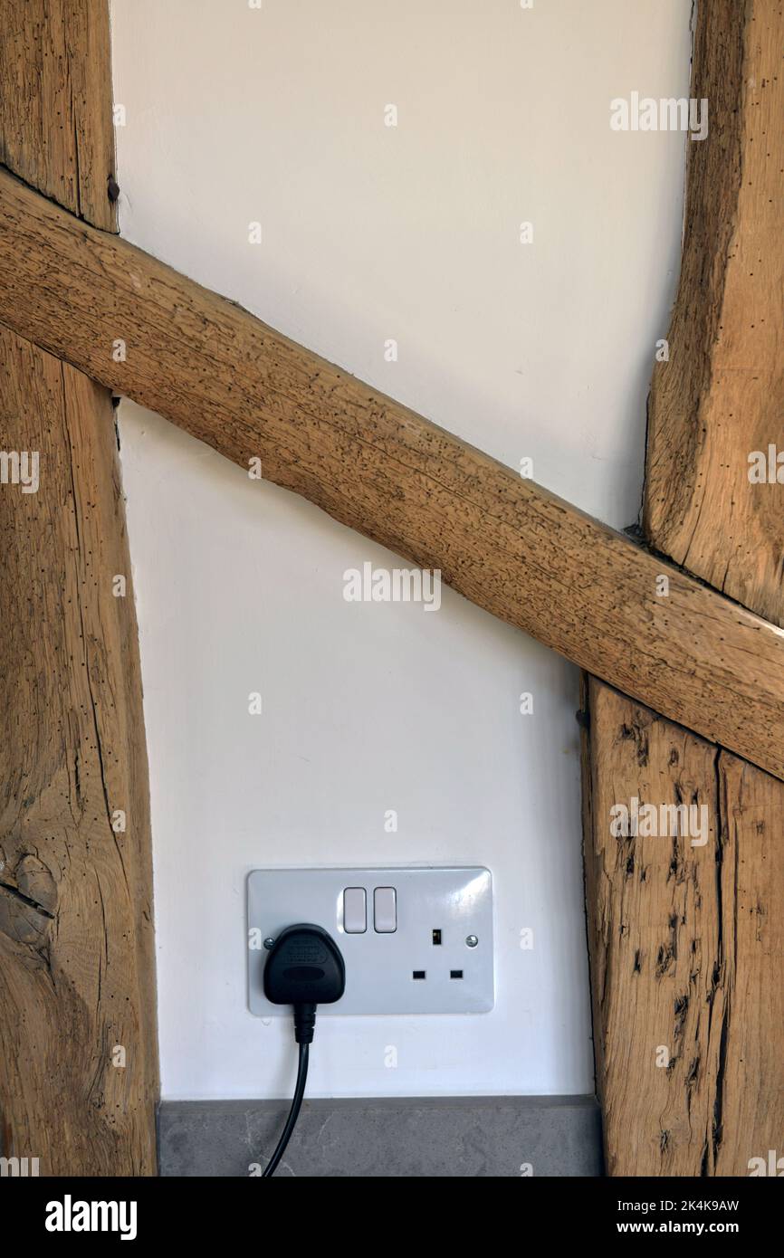 Alte Holzhausbalken und moderne 13 Ampere elektrische Steckstelle Stockfoto