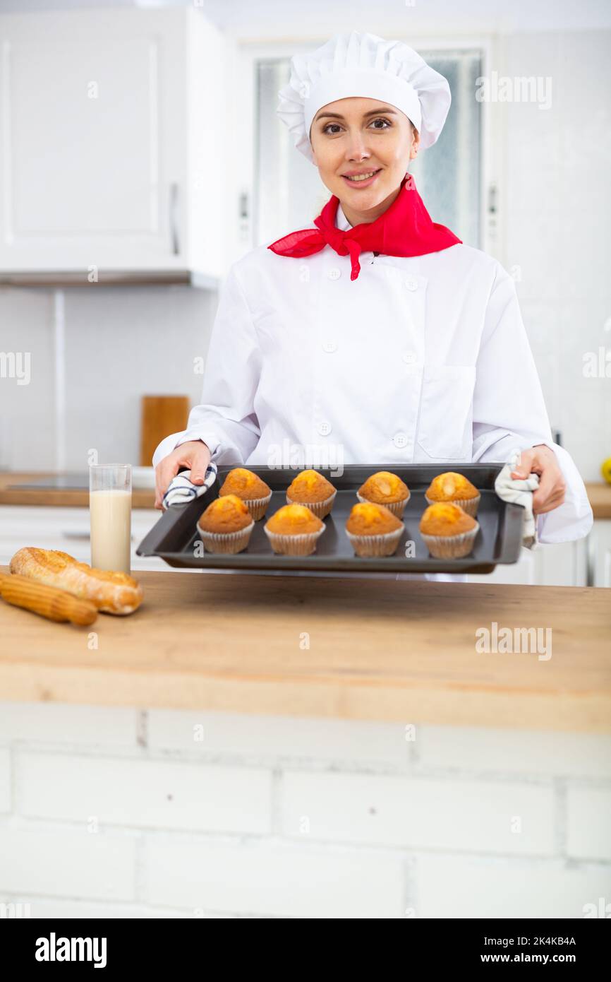 Glückliche weibliche Konditorei mit Tablett mit Cupcakes Stockfoto