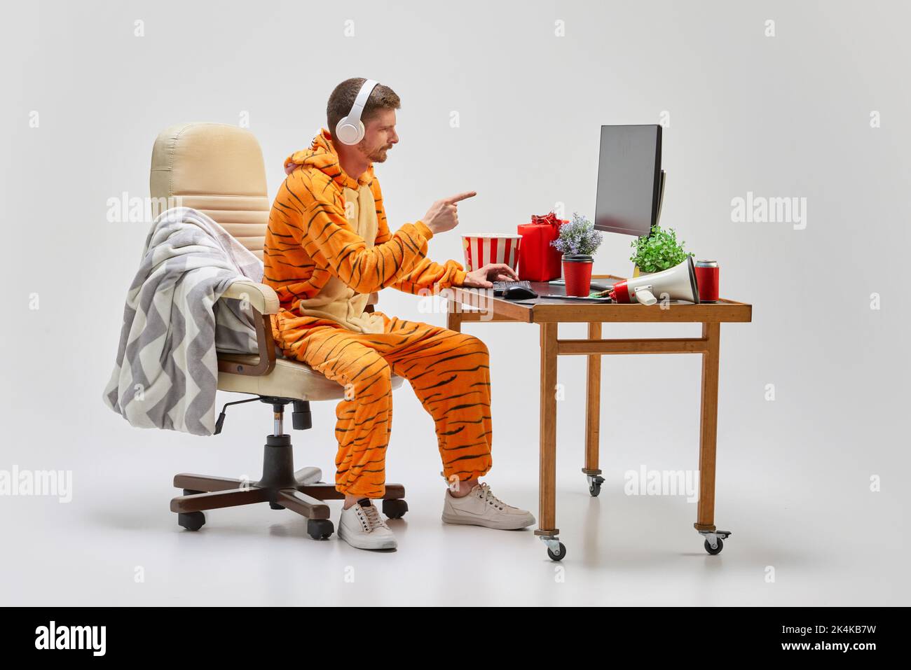 Junger Mann in erstaunlicher Kostümierung sitzt zu Hause am Computertisch. Kunst, Ideen, Kreativität, Arbeits- und Urlaubskonzept Stockfoto