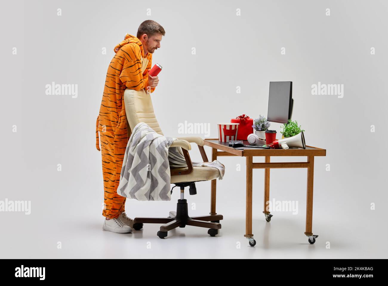 Junger Mann in erstaunlicher Kostüm von Tiger sitzt am Computer-Schreibtisch zu Hause. Kunst, Ideen, Kreativität, Arbeits- und Urlaubskonzept Stockfoto