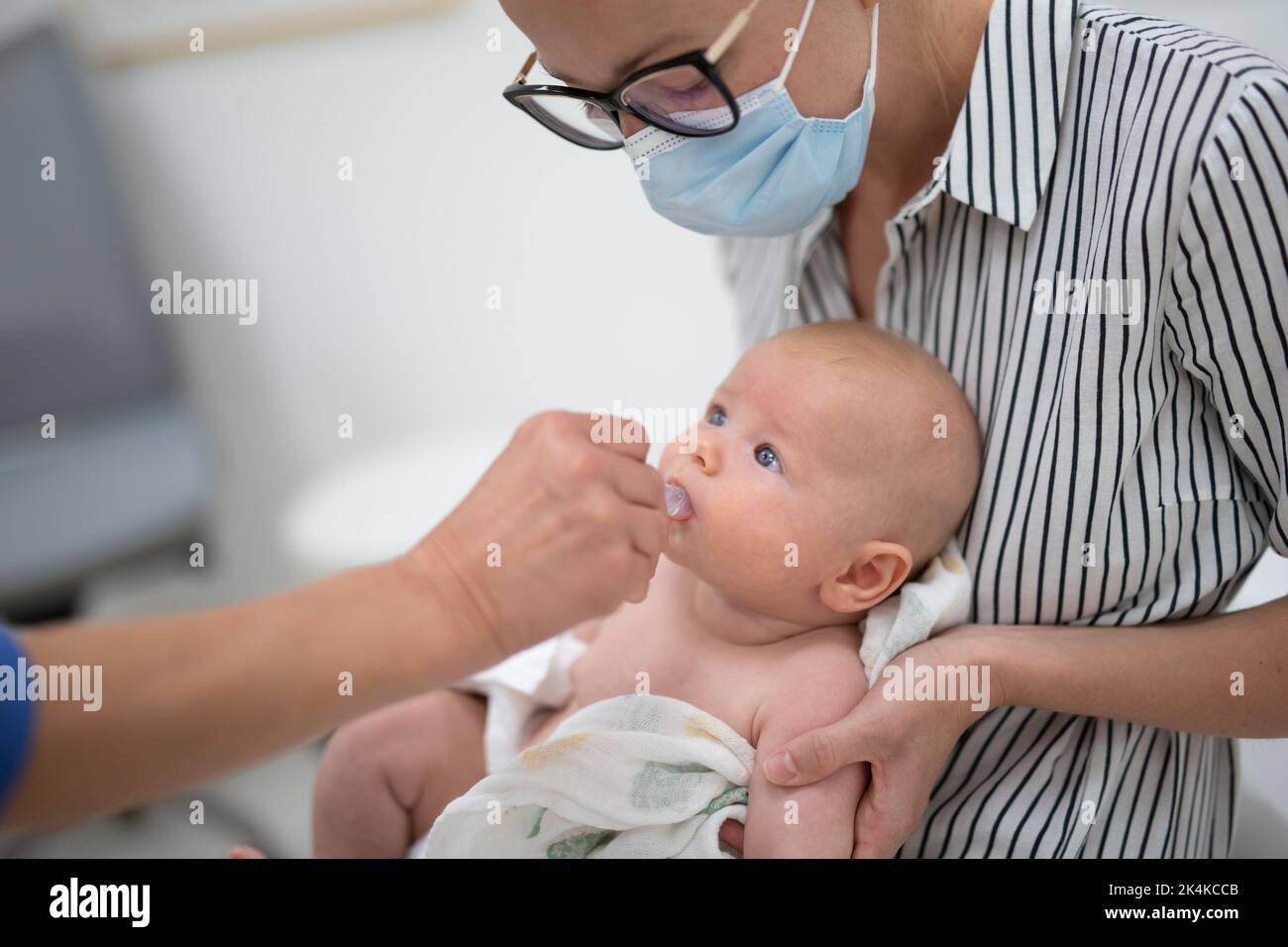 Kinderarzt, der in Anwesenheit seiner Mutter eine orale Impfung gegen Rotavirus-Infektion bei Kleinkind verabreicht. Gesundheitsversorgung und Krankheit von Kindern Stockfoto