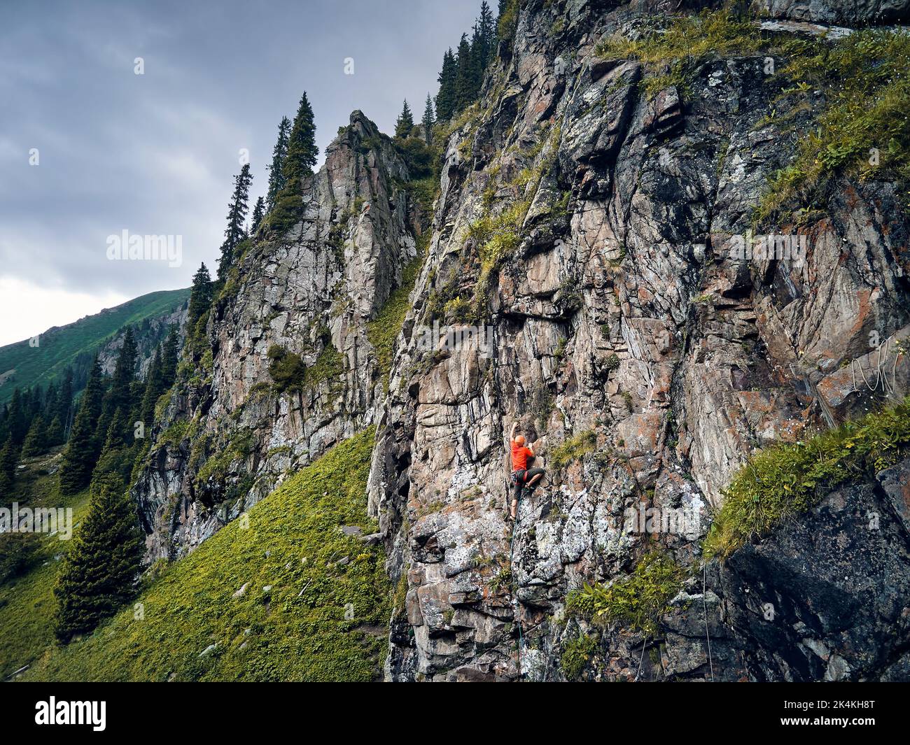 Fit starken Mann Athlet in roten Shirt Felsen Klettern an der hohen vertikalen Wand in den Bergen Tyan Shan in Kasachstan Stockfoto