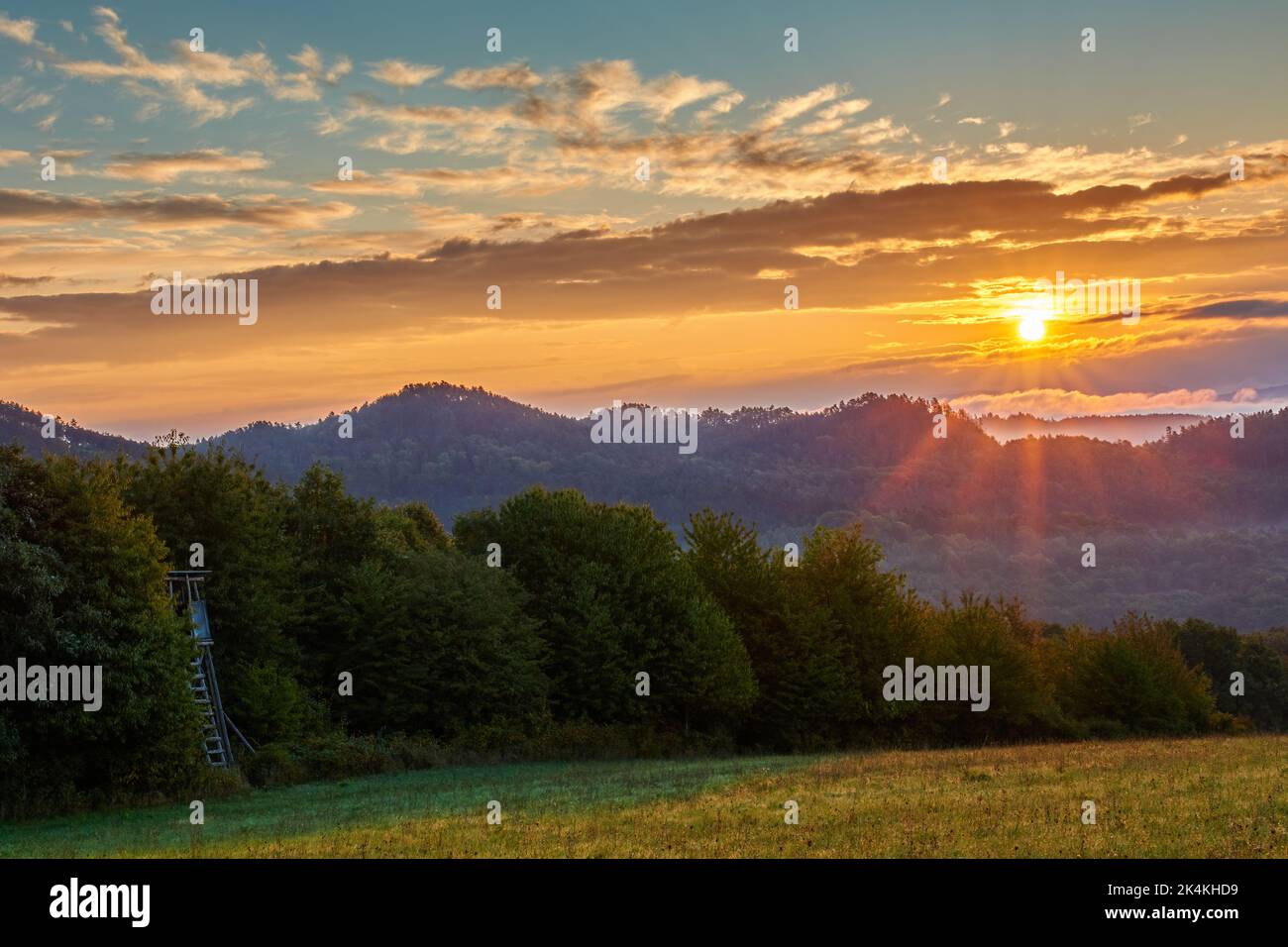 Sonnenaufgang in der Berglandschaft mit sunstar. Mit Bäumen und Hügeln im Hintergrund. Blauer Himmel, bunte Wolken. Natur Europas. Vrsatec, Slowakei. Stockfoto