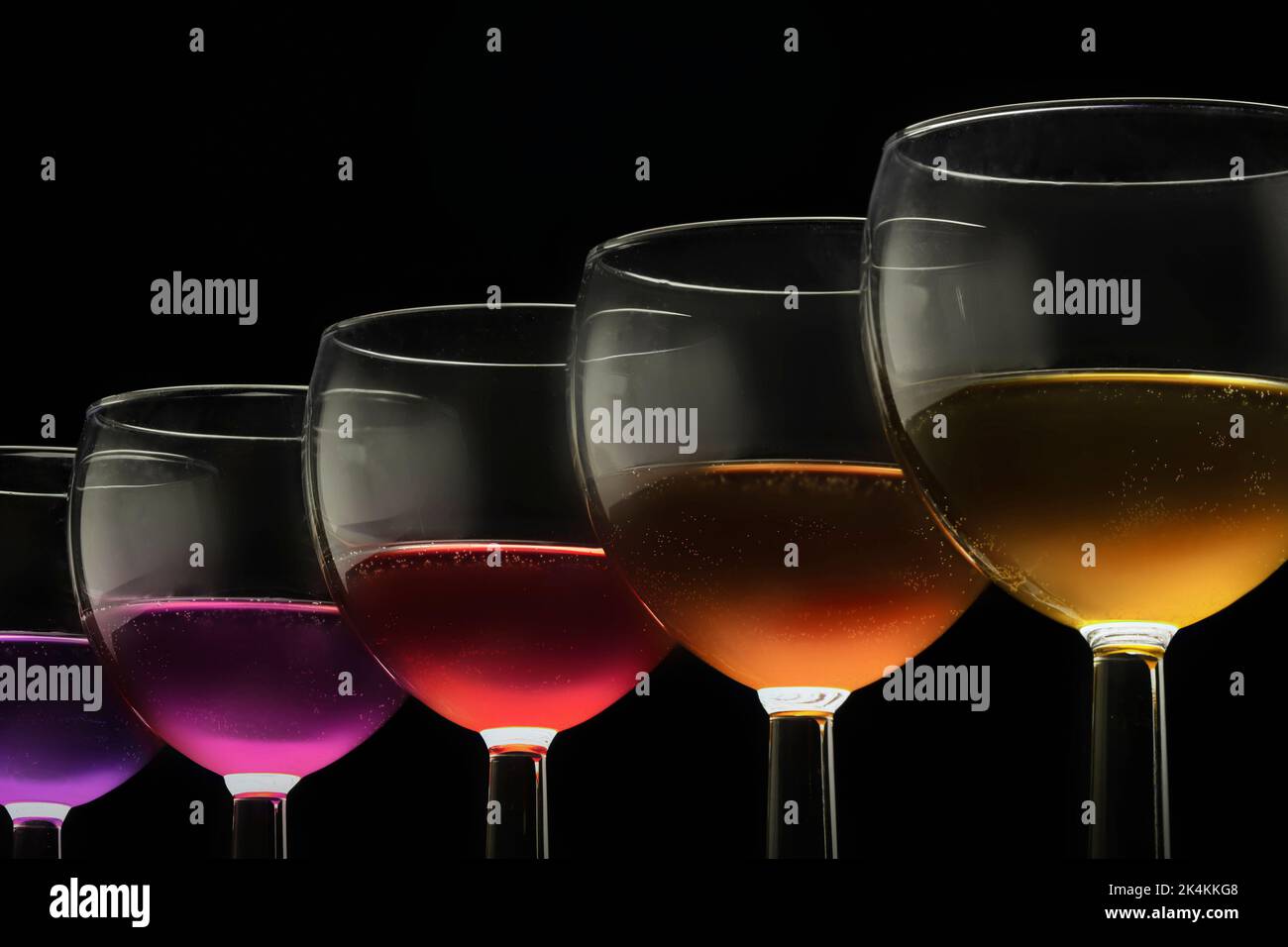 Farbige Gläser und mehrfarbiger Wein - rot gelb blau und lila orange, Wasser. Stockfoto