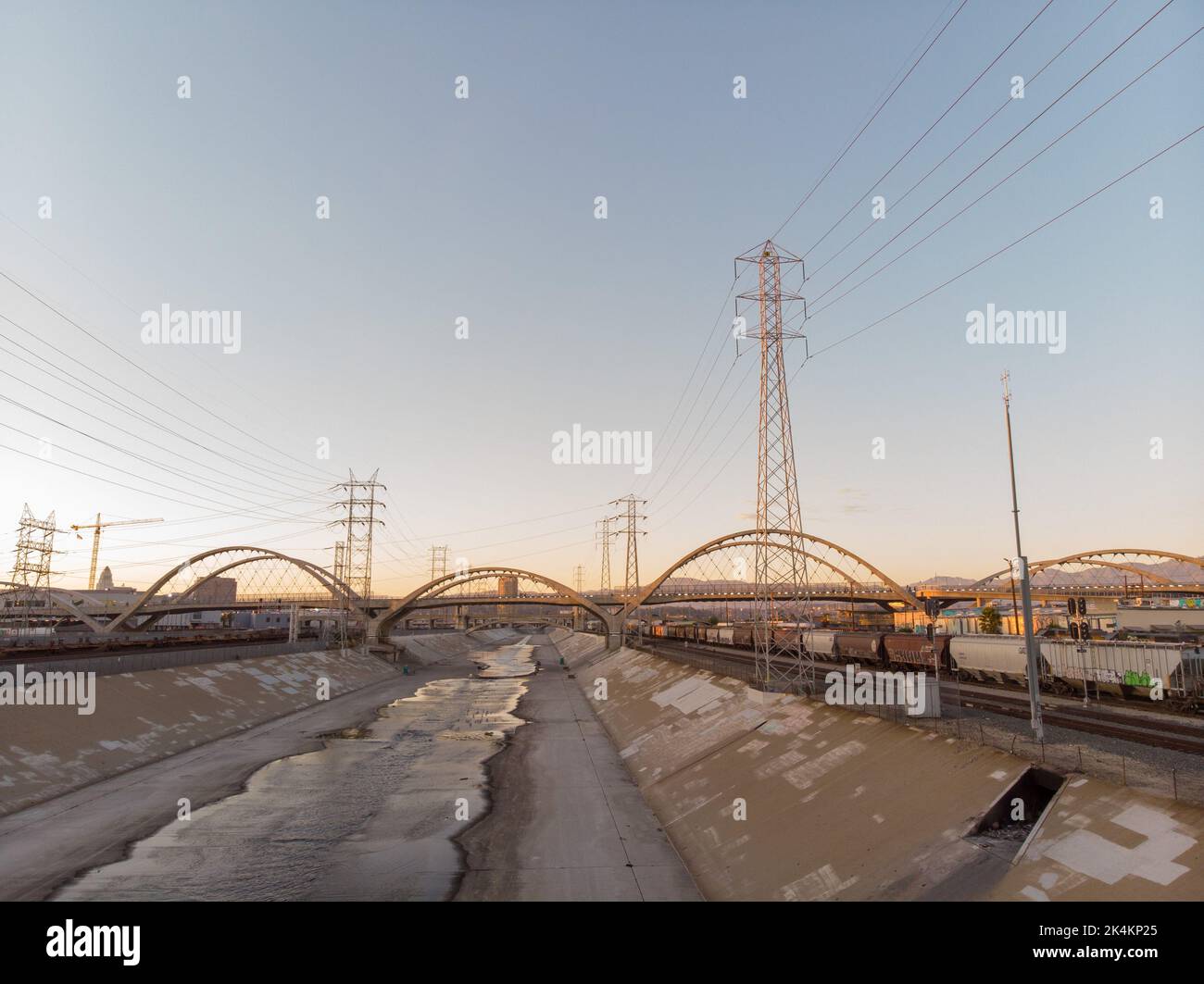 Eine Drohne, die bei Sonnenuntergang im Los Angeles River über der 6. Street Bridge fliegt Stockfoto
