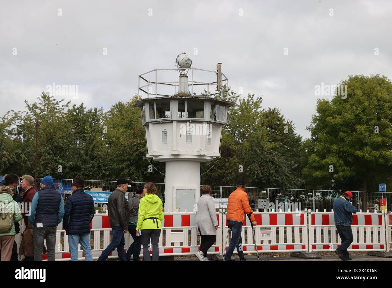 03. Oktober 2022, Thüringen, Mödlareuth/Töpen: Auf dem Gelände des Grenzmuseums am Rande des Deutschlandfestes der CSU stehen Besucher vor einem Beobachtungsturm der ehemaligen Grenztruppen der DDR. Die CSU erinnert traditionell am Tag der Deutschen Einheit an die Teilung und Wiedervereinigung Deutschlands in dem ehemals geteilten Dorf. Foto: Bodo Schackow/dpa Stockfoto