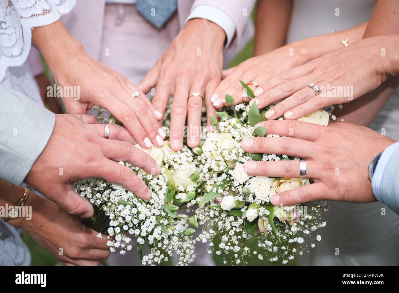 Braut und Bräutigam überreichen Hochzeitsblumen mit ihren Eheringen Stockfoto