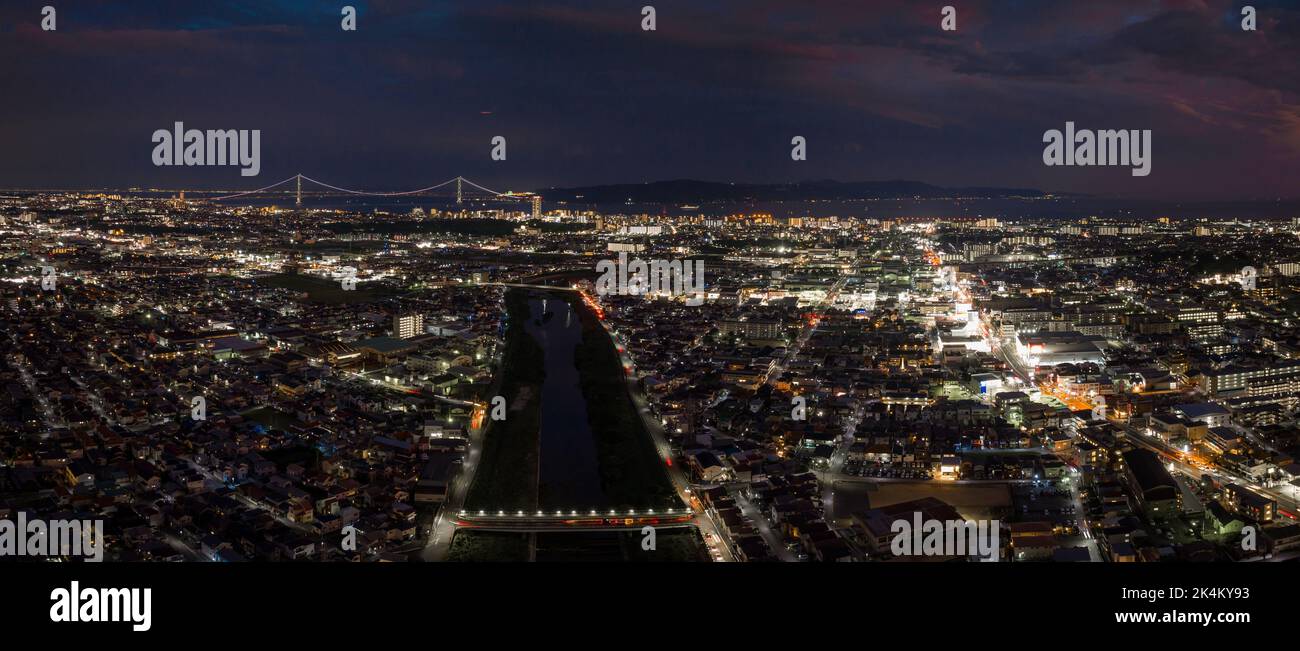 Nach Sonnenuntergang leuchten die Lichter der Stadt und die Hängebrücke in der Ferne Stockfoto