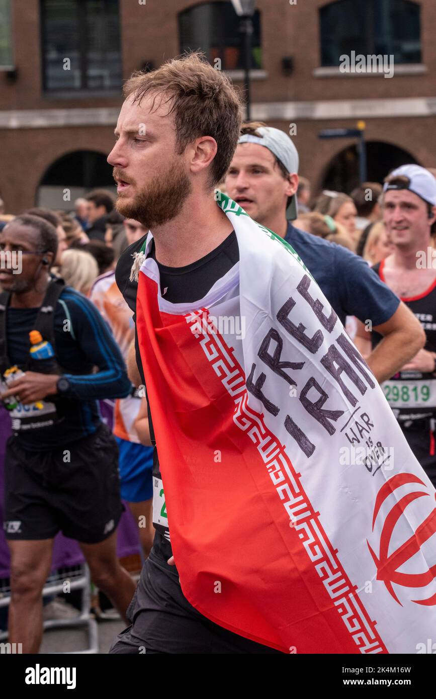 Läuferin mit einer Protestbotschaft zum freien Iran auf der Flagge beim TCS London Marathon 2022, auf der Tower Bridge Approach Road, City of London, Großbritannien. Stockfoto