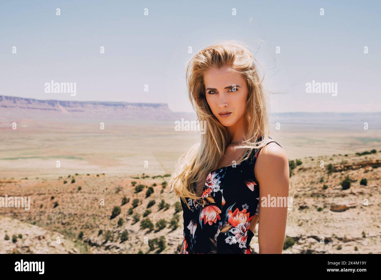 Porträt einer hübschen blonden Frau mit langen Haaren in Wüstenlandschaft Stockfoto