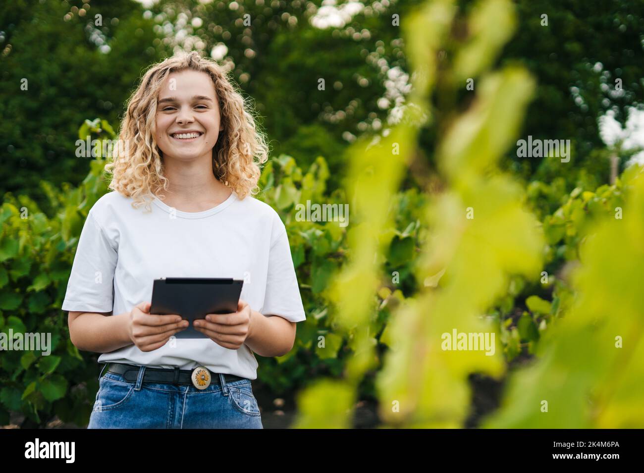 Porträt einer Farmerin mit digitalem Tablet, die auf einem landwirtschaftlichen Weinbergfeld steht. Intelligente Landwirtschaft und digitale Landwirtschaft. Futuristisch Stockfoto