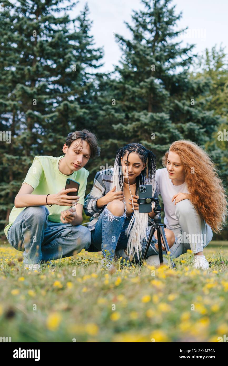 Eine Gruppe von Freunden, die im Stadtpark Handys benutzen, um Online-Inhalte anzusehen. Internet-Technologie. Schulmädchen Freunde. Internet-Netzwerk Stockfoto