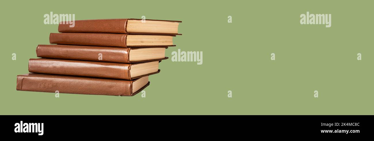 Buchstapel, Werbebanner mit grünem Hintergrund und abstrakter klassischer Literatur in braunem Hardcover. Hochwertige Fotos Stockfoto