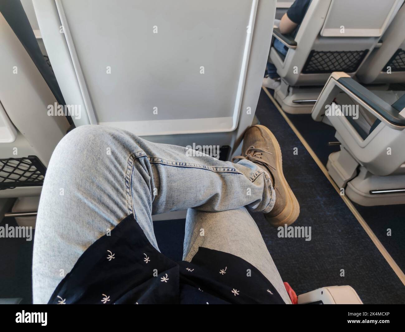 Junger Reisender, der mit gekreuzten Beinen in einem Zugwagen sitzt. Sichtbild. Stockfoto