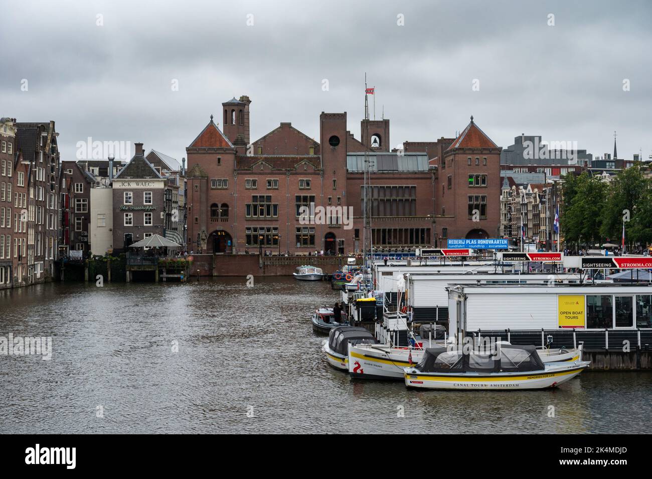 Amsterdam, Nordholland, Niederlande - Blick auf die Stadt über die Boote am Damrak-Kanal und historische Gebäude in der Altstadt. Stockfoto