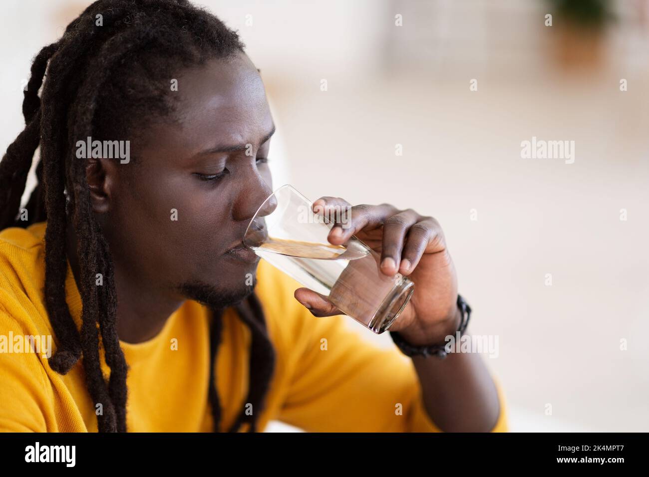Wellness-Konzept. Nahaufnahme Aufnahme Des Jungen Schwarzen Männlichen Trinkwassers Aus Glas Stockfoto