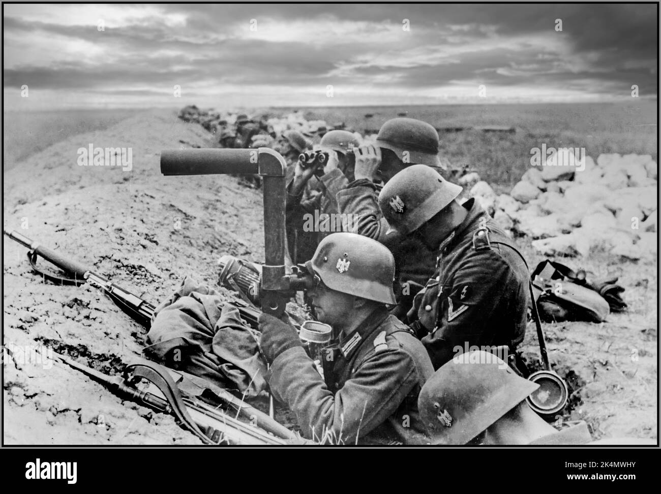 OPERATION BARBAROSSA WW2 Deutsche Infanterie in den Schützengräben der Ostfront beobachtet einer der Soldaten die sowjetischen Positionen mit SF14ZGi Ferngläsern. Eines der einzigartigsten optischen Schlachtfeld-Systeme aus dem Zweiten Weltkrieg, das von Leitz, dem Hersteller der Leica-Kamera, entwickelt wurde. Dieser Hybrid zwischen Fernglas und Periskop ermöglichte es dem Betrachter, sicher verborgen zu bleiben, wobei nur die objektive Linse für den Feind sichtbar war. Die Wehrmacht nutzte sie für die allgemeine Beobachtung (in Fahrzeugen und am Boden) und für die Überwachung und Richtung des Artillerieballes. Datum Oktober 1941 Stockfoto