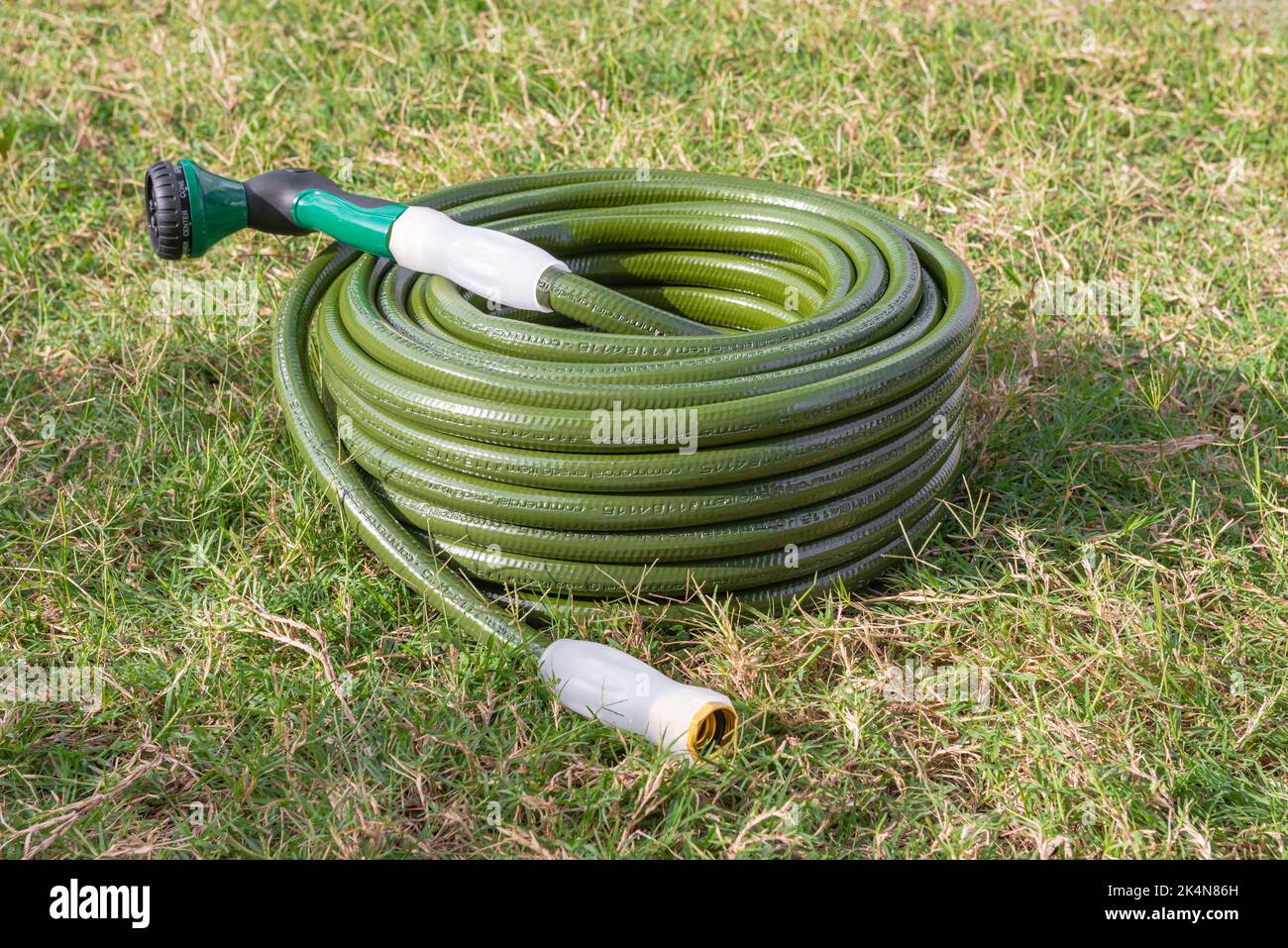 Gartenschlauch grünen Rasen neue Gartengeräte eingewickelt bis gewickelt Stockfoto