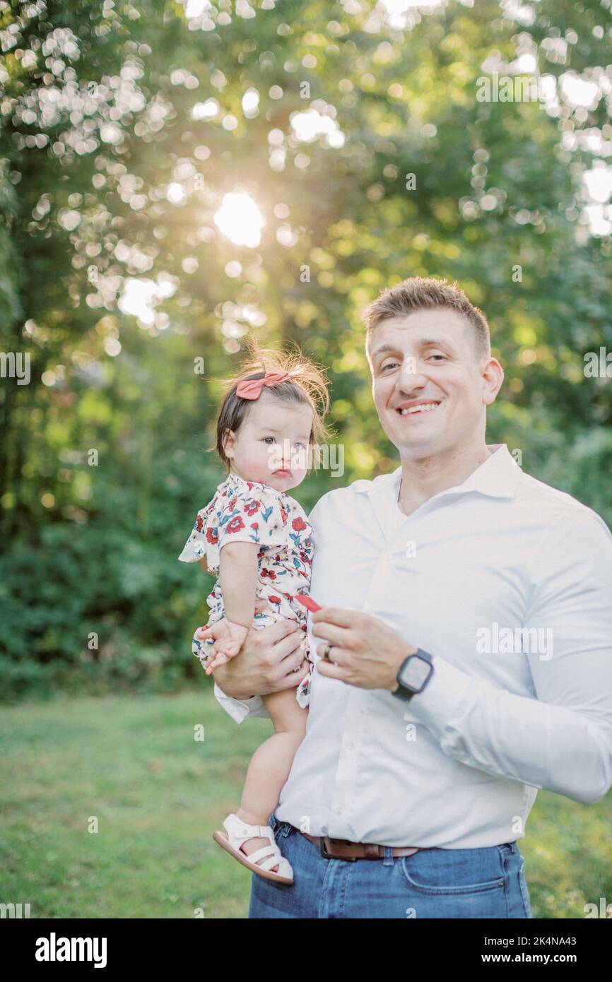 Der kaukasische Vater hält am Sommertag eine 1-jährige Tochter. Stockfoto